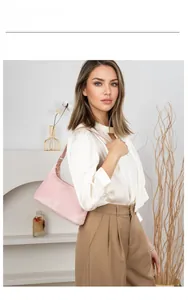 Pink suede underarm shoulder bag with adjustable strap worn by model in a minimal setting