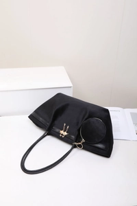 Détail du sac cabas en velours noir avec pendentif cygne doré et pochette ronde assortie