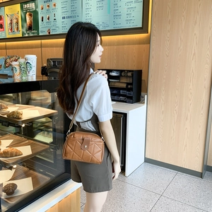 Brown quilted crossbody phone bag with retro buckle worn by model in a cozy cafe