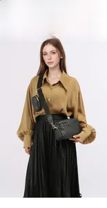 Dettaglio di un set di borse a tracolla in jacquard nero e pochette rotonda su una modella