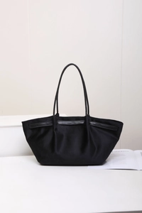 Détail d'un sac cabas noir minimaliste au design plissé avec de fines anses doubles