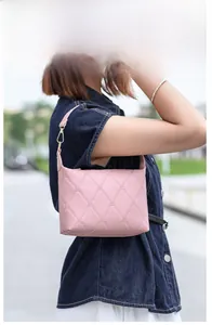 Detail einer rosa gesteppten Handtasche mit Rautenmuster und goldenen Metallelementen