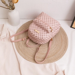 Pink mini backpack with geometric prints and gold hardware on a stylish straw mat