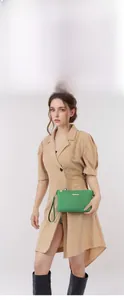 Detail of green faux-snake leather mini bag with gold chain strap and metal logo plate