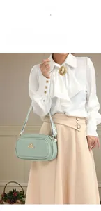 Detail of mint green crossbody bag featuring a wide geometric strap and gold logo