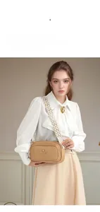 Detail of brown litchi pattern camera bag with gold logo and jacquard strap