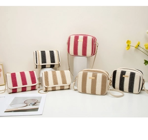 Detail view of striped straw woven bags with golden chain straps and metallic zippers
