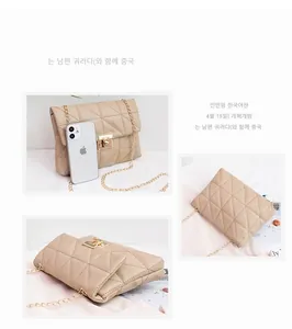 Macro detail of beige quilted crossbody bag with gold chain and metal buckle