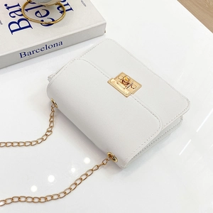 Petit sac carré blanc avec bandoulière chaîne dorée et fermoir sur un bureau blanc