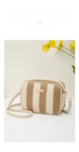 Detail of striped straw camera bag with gold hardware and ivory leather strap