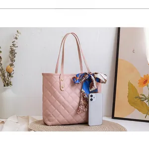 Pink quilted tote bag with silk scarf handle detail shown beside a smartphone for scale