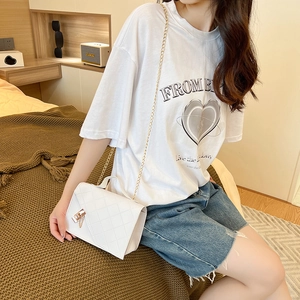 White quilted square bag with gold chain strap shown in a cozy bedroom setting