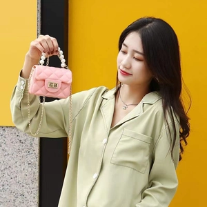 Close-up of pink quilted jelly bag featuring pearl handle and gold chain strap details