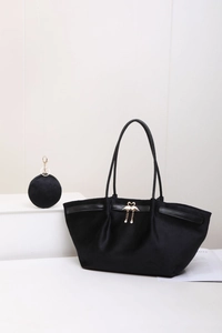 Détail du sac cabas en daim noir avec boucle flamant rose dorée et breloque à pompon