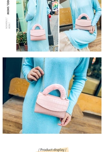 Detail of pink croc-embossed bag with plush handle and gold chain on light blue dress