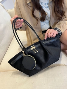 Détail du cabas en velours noir avec boucle de cygne dorée et petit porte-monnaie
