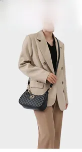 Model wearing a retro monogram saddle bag with golden M logo and adjustable strap