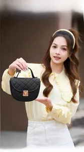 Détail d'un mini sac à main matelassé noir avec fermoir doré et base en forme d'arc