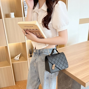 Chic black quilted crossbody bag with golden chain strap and metal lock in a modern setting
