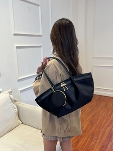 Détail du sac cabas plissé noir avec pendentif oiseau doré et petit porte-monnaie