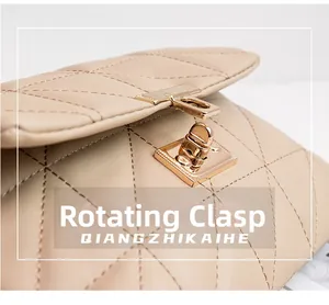 Detailed close-up of a golden twist lock closure on a beige quilted crossbody bag