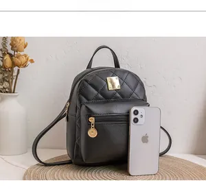 Detail of black quilted mini backpack showing its size next to a smartphone