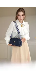 Detail of dark blue cross-body camera bag with wide geometric patterned woven strap