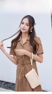 Detail of a beige woven envelope bag with gold hardware held by a model