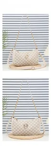 Detail of beige crescent bag featuring M-letter monogram pattern and gold metal logo
