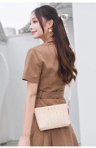 Detail of light beige woven straw crossbody bag with gold logo and leather strap