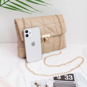 Quilted beige chain crossbody bag with gold lock shown next to mobile phone for size