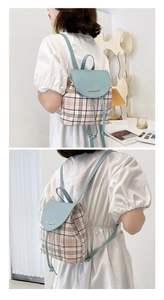 Dettaglio dello zaino a quadri blu e beige con coulisse e logo dorato elegante