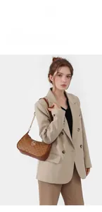 Detail of vintage brown monogram handbag featuring gold chain strap and metal logo accent