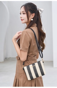 Detailed view of black and white woven crossbody bag with gold logo and leather strap