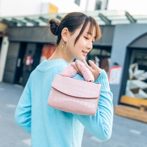 Pink faux crocodile leather handbag with plush fur handle shown on model in street setting