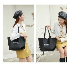 Photo lifestyle d'un grand sac cabas noir en cuir avec imprimé MIKAXIQI porté à l'épaule