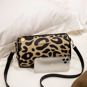 Leopard print cylinder crossbody bag with black leather strap and golden hardware