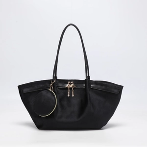 Sac tote en velours noir avec breloques cygne dorées et porte-monnaie rond sur gris