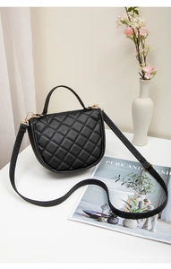 Détail du sac selle matelassé noir avec finitions dorées et large bandoulière