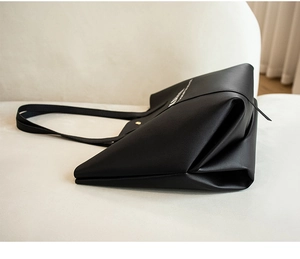 Détail du sac cabas en similicuir noir montrant la base pliable et le fini texturé