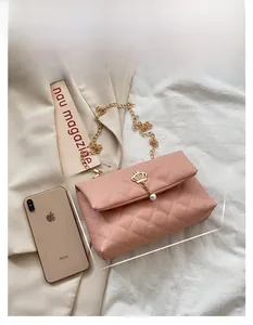 Pink quilted shoulder bag detail with gold crown charm and pearl on elegant chain strap