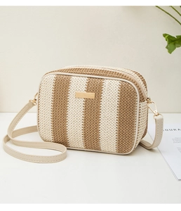 Close-up of woven straw texture and gold metal plaque on the striped crossbody bag