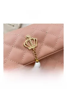 Detailed close-up of pink quilted leather with golden crown hardware and pearl charms