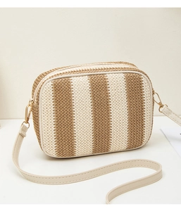 Close-up of a striped straw woven camera bag featuring beige leather trim and gold hardware