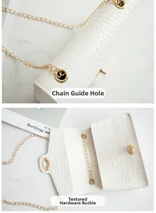 Detail der Goldkettenlöcher und des ovalen Drehverschlusses an weißer Kroko-Handtasche