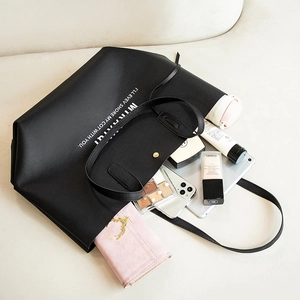 Grand sac cabas noir en cuir avec lettrage blanc montrant sa grande contenance