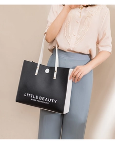 Detail of contrast stitch tote bag with Little Beauty text and metal rivet hardware