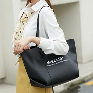 Grand sac cabas noir mat avec lettrage blanc porté par un mannequin en extérieur