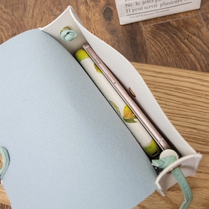 Petit sac bandoulière bleu ciel montrant sa capacité intérieure pour smartphone et objets