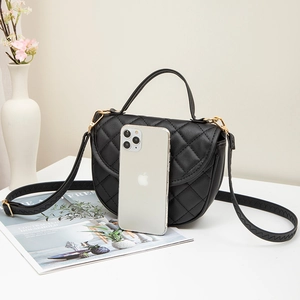 Sac selle matelassé noir avec finitions dorées et smartphone pour comparer la taille